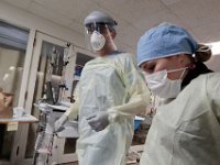 Dr. Michael Barretti and nurse, Jennifer Soares, suit up to check in on a patient infected with COVID-19 in the ICU at St. Luke's Hospital in New Bedford.  PHOTO PETER PEREIRA