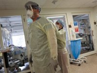 Dr. Michael Barretti and nurse, Jennifer Soares, suit up to check in on a patient infected with COVID-19 in the ICU at St. Luke's Hospital in New Bedford.  PHOTO PETER PEREIRA