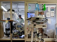 Dr. Michael Barretti, checks in on a COVID-19 patient in critical condition inside one of the sealed rooms of the St. Luke's Hospital ICU in New Bedford, MA. PHOTO PETER PEREIRA