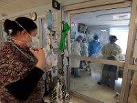 Respiratory therapist, Deborah Sironen, left, looks on as nurses inside one of the sealed rooms used for COVID-19 patients in Knowles Wing at St. Luke's Hospital in New Bedford prepare a patient to be moved for surgery.  PHOTO PETER PEREIRA