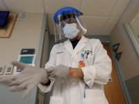 Dr. Umesh KC puts a fresh pair of gloves one before visiting a patient at St. Luke's Hospital in New Bedford.  PHOTO PETER PEREIRA