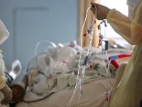 A nurse hold up all of the medication lines for a patient infected with COVID-19 before he is transferred to surgery at St. Luke's Hospital in New Bedford.  PHOTO PETER PEREIRA