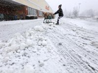 A woman fights to drag her shopping cart to her vehicle after exiting the Shaws Supermarket in Dartmouth, MA as a snow storm sweeps across the area.  [ PETER PEREIRA/THE STANDARD-TIMES/SCMG ]