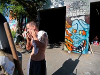 ma nb HomelessinTheWoods  James Soares, 50, shaves near where he lives in the woods behind Save-A-Lot in the north end of New Bedford, in the background 'Papa Doc' is seen sitting in the shade of a bock building he lives in.   PETER PEREIRA/THE STANDARD-TIMES : poverty, homeless, woods