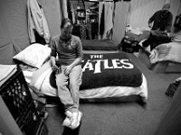 Robert Pichette, sits on his bed, while one of his roommates is seen in the background putting his clothes away at the House of Hope in New Bedford. The House of Hope houses over 50 homeless people and has self  quarantined for over three weeks due to the coronavirus pandemic.  No one is allowed in or out of the shelter.  PHOTO PETER PEREIRA