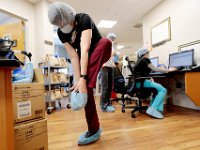 Physical therapist, Sue Abbott, prepares to check in on a patient by placing protection on her feet at the Charlton Memorial Hospital in Fall River.  PHOTO PETER PEREIRA