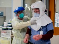 David Scola, radiology tech, wipes down the PAPR hood of Dr. Hector Mateo after he left the room with a COVID-19 patient at the Charlton Memorial Hospital in Fall River.  PHOTO PETER PEREIRA