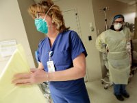 Betty Chandler, RN preapres to don her gown, as she and Katelin Arruda, nurse tech, prepare to go into a room with a newly admitted patient in the ER at Tobey Hospital in Wareham.  PHOTO PETER PEREIRA