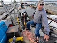Bill Wilbur of Triad Boatworks drives the submersible unit boat carrier out of Mattapoisett harbor as Silas Costa can be seen on deck preparing the rigging, as owners rush to remove their boats before an expected storm sweeps across the region. PHOTOGRAPHER NOTE:  Mattapoisett harbor is simply fantastic during summer time with all of the sailboats tied to their moorings.  But what goes in, must eventually come out, and I had a feeling that boaters were getting anxious to get their sailboats out of the water as high winds began sweeping across the region.  When I arrived, I noticed this gentleman sitting on top of the weird contraption they use to take the boats out.  I proceeded to climb up, and then it was just a matter of waiting for the perfect moment.  In this case notice how the man on the sailboat is busy with the line, while the driver has his hand on the gear as the apparatus moves forward.  Did I mention that I was hanging off the front of the vehicle?  The stuff we do to get a good photo... [ PETER PEREIRA/THE STANDARD-TIMES/SCMG ]