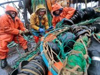 Under driving rain, fishermen aboard the New Bedford fishing boat Sao Paulo, (l to r) Tony Borges (owner/captain), Joao Gomes, and Joshua Azul  change the nets from groundfish, to fluke netting in preparation for January 1st when the new fluke regulations will be put into effect.  [ PETER PEREIRA/THE STANDARD-TIMES/SCMG ]
