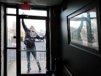 Douglass Cutler of All Clean Window Cleaning is reflected on a photo on the wall, as he gives the window door of dNB on Elm Street in downtown New Bedford a wash. [ PETER PEREIRA/THE STANDARD-TIMES/SCMG ]