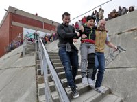 Hayden McFadden teachers, Michael Roderick, left, and physical education teacher Brian Coon, give fifth grader, Daniel Bejarano Alvarado, who injured his knee outside of school,  a hand going down the stairs, so that he could be closer to his classmates during the egg-drop in front of their school in New Bedford.  [ PETER PEREIRA/THE STANDARD-TIMES/SCMG ]