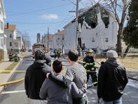 Branden Padilla, center, is given comfort by his cousin, as they watch New Bedford firefighters respond to a fire that broke out at Mr. Padilla's residence at 11 Spruce Street.   [ PETER PEREIRA/THE STANDARD-TIMES ]