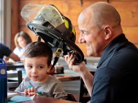 New Bedford firefighter Ronald Crowell who was grabbing a cup of coffee at Tia Maria's European Cafe, offers to show his firefighter helmet to Karter Conchinha, 2, who was there having breakfast with his family.  [ PETER PEREIRA/THE STANDARD-TIMES/SCMG ]