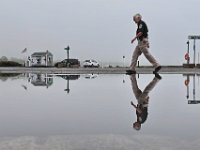 Mattapoisett harbormaster Jill Simmons seemingly walks on water as she makes her way across the Freddie Brownell Wharf in Mattapoisett, past a large puddle of water from the heavy overnight rains.  [ PETER PEREIRA/THE STANDARD-TIMES/SCMG ]