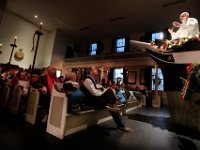 Candles provide the only light, as parishioners look as Pastor Paul Wheeler of the Trinity Lutheran Church. conducts the annual Christmas Candlelight Service from the iconic pulpit inside of the historic Seamen's Bethel in New Bedford [ PETER PEREIRA/THE STANDARD-TIMES/SCMG ]