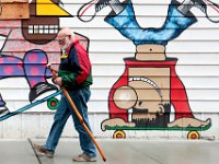 A man with a walking stick makes his way past a mural painted on the side of a building on Pleasant Street in downtown New Bedford.  [ PETER PEREIRA/THE STANDARD-TIMES ]