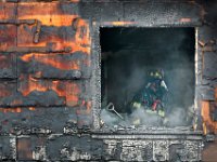 A New Bedford firefighter can be ssen inside the charred walls of a single family home which caught fire on Tremont Street in New Bedford.  [ PETER PEREIRA/THE STANDARD-TIMES ]