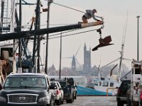 The iconic Fairhaven skyline can be seen in the distance, as a fisherman finds himself high above the pier in New Bedford  making repairs to a fishing boat's outrigger.  [ PETER PEREIRA/THE STANDARD-TIMES/SCMG ]