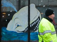 New Bedford police officer Pedro Moco, directing traffic on Union Street in downtown New Bedford, is unaware of a friend drawn on the windows of the Moby Dick Brewery restaurant.  [ PETER PEREIRA/THE STANDARD-TIMES ]
