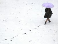 A woman leaves her footprints behind, as she makes her way across a snow covered Times Square parking lot in New Bedford. .  [ PETER PEREIRA/THE STANDARD-TIMES/SCMG ]