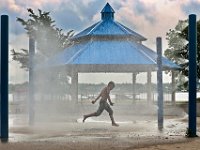 A youngster flies through the air as he takes shelter from the heat by running through the sprinklers at Riverside Park in the north end of New Bedford.  [ PETER PEREIRA/THE STANDARD-TIMES/SCMG ]
