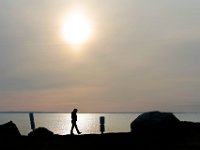 A woman goes for an early morning walk around Ned's Point in Mattapoisett, as the sun rises in the distance.  [ PETER PEREIRA/THE STANDARD-TIMES/SCMG ]