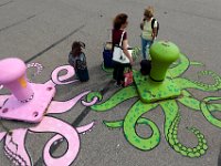Two women who had just arrived on the ferry from Nantucket, are entraped by the octopi painted bollards, as they wait for their ride to arrive at State Pier in New Bedford.