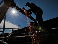 Joao Lopes of Luzo Welding Services sends spakrs flying as he uses a cutter to put a hole in a new outrigger he is installing on the Seven Seas fishing boat in New Bedford.