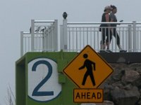 Two signs comined rightfully point out that two pedestrians are walking atop the Harborview Walk in the sound end of New Bedford.  The large two signifies that this is the second storm barrier door which can be closed if a hurricane or storm were to strike the region.