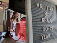 A sign outlining the fact that this is her first year, sits in front of her computer, as Courtney Lima logs onto her computer to begin her first school day as a teacher. Courtney Lima who attended the Taylor School in New Bedford as a student for grades K-6, returns for her first day of school, this time as a third grade teacher. Ms. Lima will be teaching third graders virtually this year, as part of the Distance Learning Academy for students who opted to stay home for this school year.  PHOTO PETER PEREIRA]