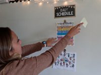 Courtney Lima pulls a sticky note from the schedule posted on her whiteboard. Courtney Lima who attended the Taylor School in New Bedford as a student for grades K-6, returns for her first day of school, this time as a third grade teacher. Ms. Lima will be teaching third graders virtually this year, as part of the Distance Learning Academy for students who opted to stay home for this school year.  PHOTO PETER PEREIRA