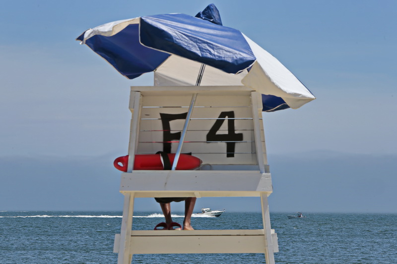 A lifeguard looks on from his observation tower as a boat makes its way out to sea on East Beach in the south end of New Bedford, MA.  PHOTO PETER PEREIRA