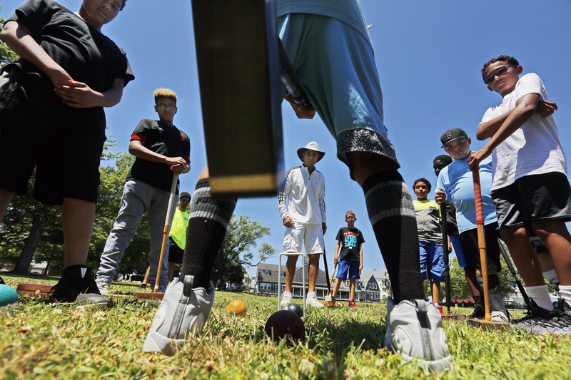 International and American Croquet Champion Sherif Abdelwahab, center,  looks on as a Youth Opportunities Unlimited participant uses a mallot to drive the ball  through the wickets as try their hand at croquet at Hazerlwood Park in the south end of New Bedford, MA. PHOTO PETER PEREIRA