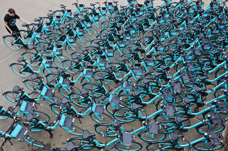 Anne Coulter helps unload 100 VeoRide bicycles from a truck onto a parking lot at Umass Dartmouth.  The dockless bike share system will be distributed throughout the UMass Dartmouth campus, for students to use. PHOTO PETER PEREIRA