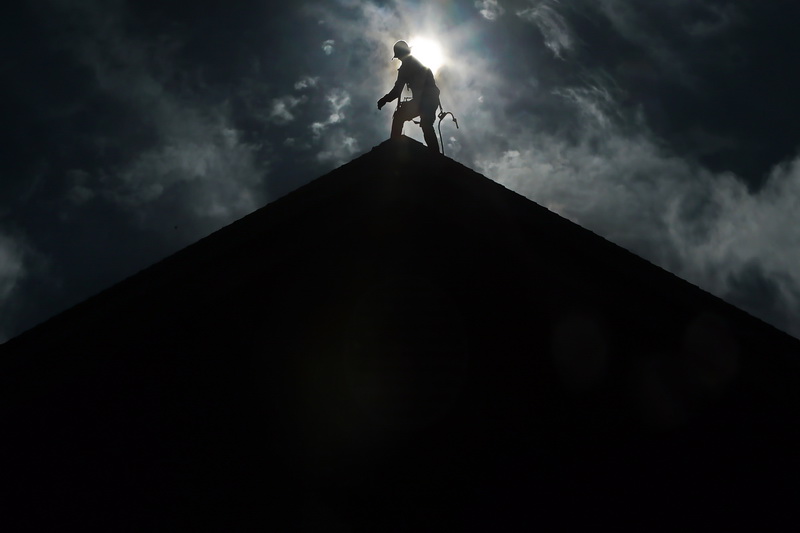 The sun rises behind a workman installing a new roof on the Mattapoisett police station. PHOTO PETER PEREIRA