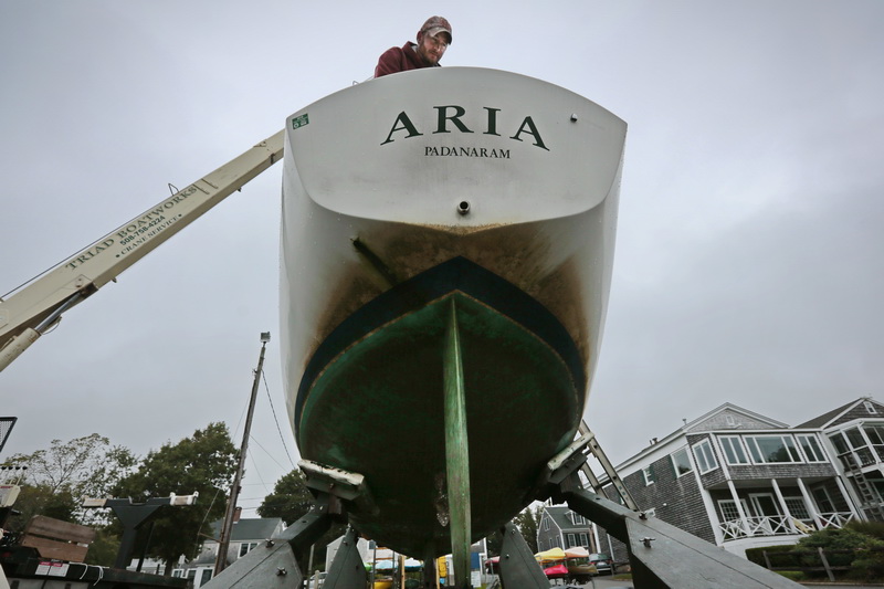 Jason Costa, of Triad Boatworks, goes about removing the rigging from the Aria sailboat that they just pulled out of Mattapoisett harbor. PHOTO PETER PEREIRA