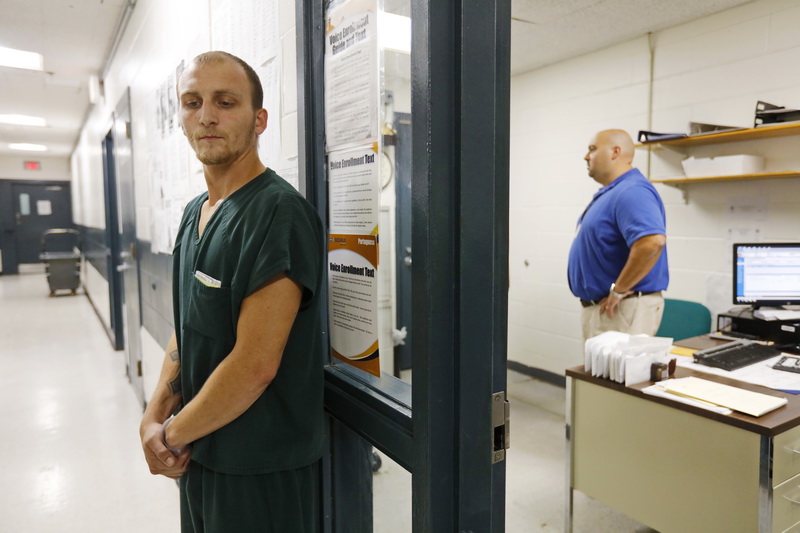 Inmate, Daniel Keyes, listens for his name to be called for a video bail hearing, as director of intake services, Kenneth Souza, establishes a video link to the Fall River courtroom inside his office at the Bristol County House of Correction in Dartmouth, MA. PHOTO PETER PEREIRA