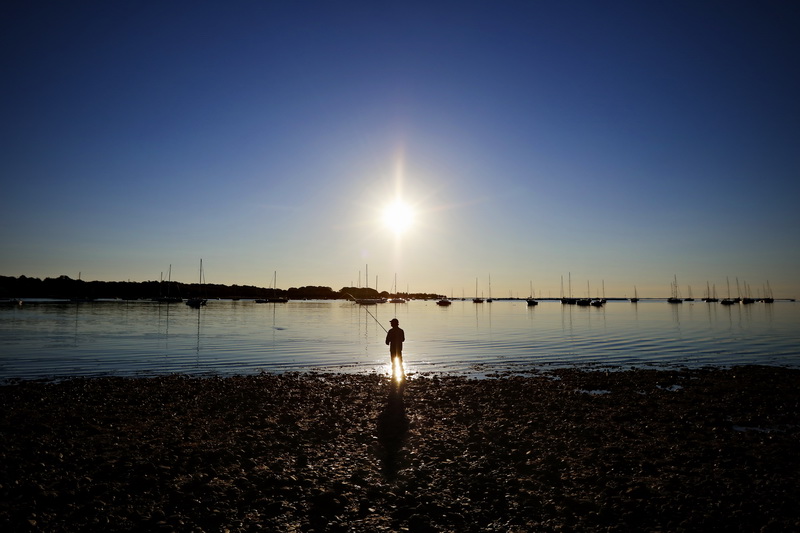 A man casts his line into Padanaram harbor in Dartmouth, MA as the sun rises in the background.    PHOTO PETER PEREIRA