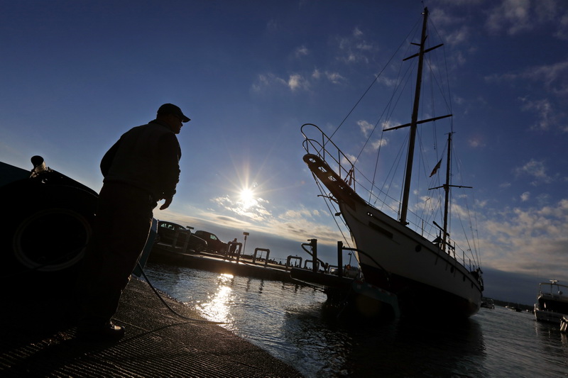 The sun rises in the distance as Tom Checkman of Brownell Systems, pulls the 50 foot sailboat, Kismet, from Mattapoisett harbor.  PHOTO PETER PEREIRA