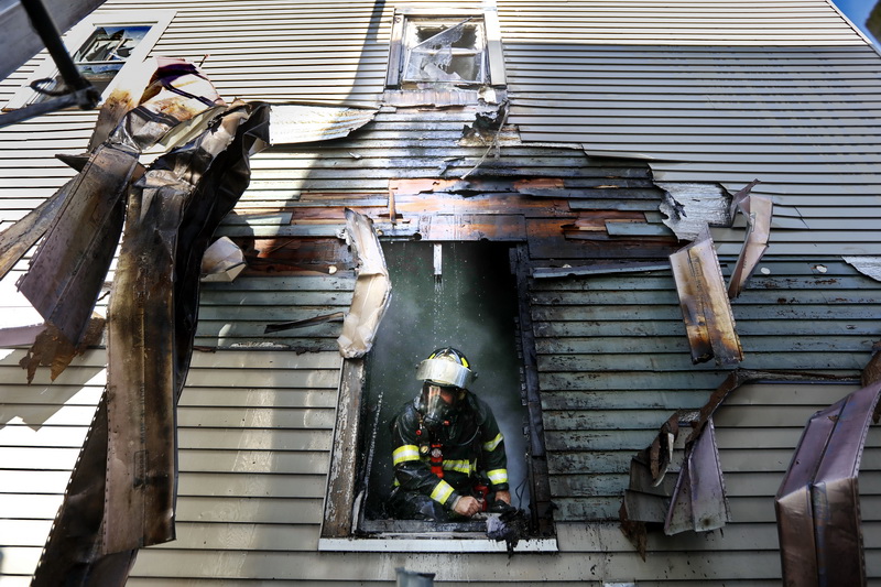 A New Bedford firefighter is seen throught the window of the kitchen where a fire started at 280 Sawyer Street in the north end of New Bedford, MA. PHOTO PETER PEREIRA