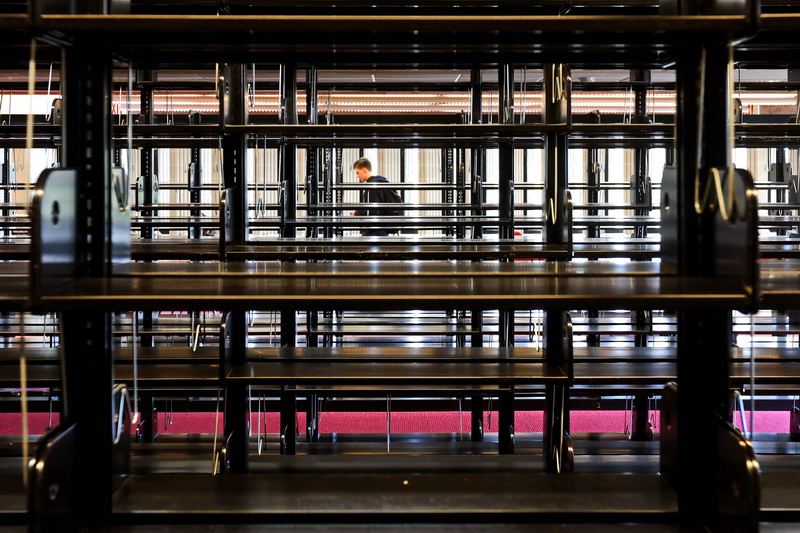 A student walks past some shelves that are being restocked  in the UMass Dartmouth library in Dartmouth, MA. PHOTO PETER PEREIRA