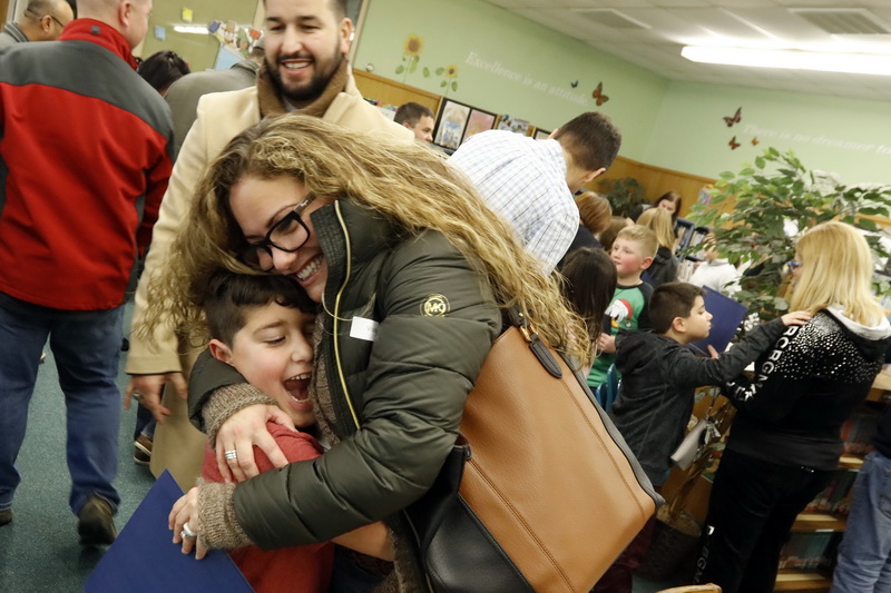 (above) Kevin Lazaro, father, looks on as a jubilant second grader Julian Lazaro, 7, casts himself at his proud mother, Claudia Lazaro, after receiving his citation from Governor Baker for his participation in the Scholastic Summer Reading Challenge, which the Quinn Elementary School in Dartmouth, MA won for the fourth consecutive year. (below) Fifth graders, Rowan Desautels, 11, and Kaitlyn Falcon, 10, look for the next book they will read at the Quinn Elementary School library.  PHOTO PETER PEREIRA