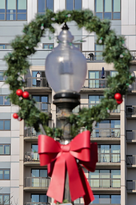A resident of the Regency Towers is seen through a wreath around the streetlight on Purchase Street in downtown New Bedford, MA.  PHOTO PETER PEREIRA