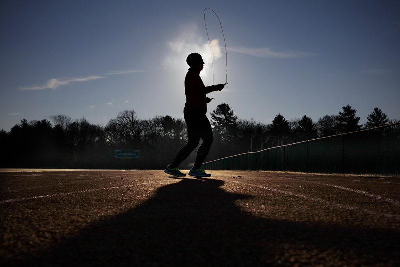 The sun rises in the distance as steam rises from her breath and head while Liddy Pepin works on her fitness routine by jumping rope on the track at UMass Dartmouth on a cold morning in Dartmouth, MA.     PHOTO PETER PEREIRA