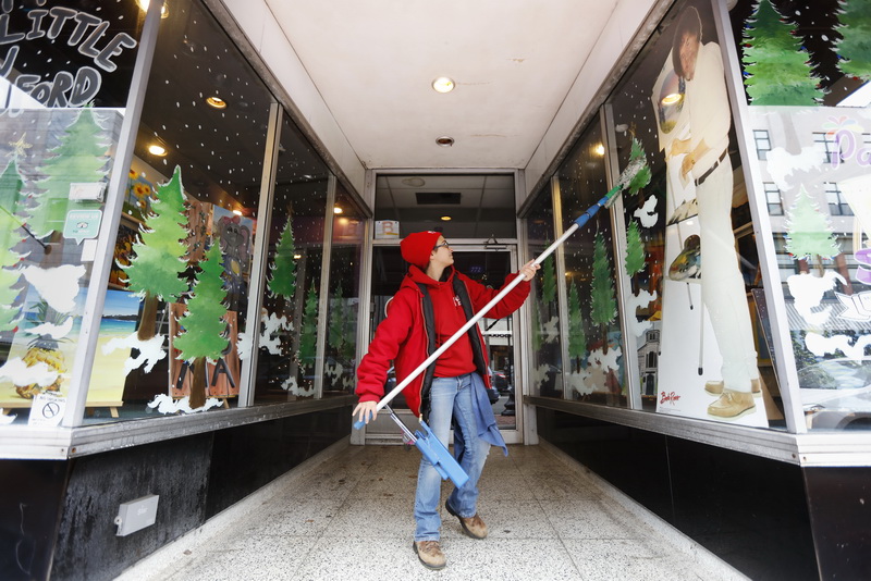 Rebecca Souza of Fish Window Cleaning, cleans the storefront windows of Painting with a Splash on Purchase Street in New Bedford, MA, and gives Bob Ross a fresh outlook in the process.     PHOTO PETER PEREIRA