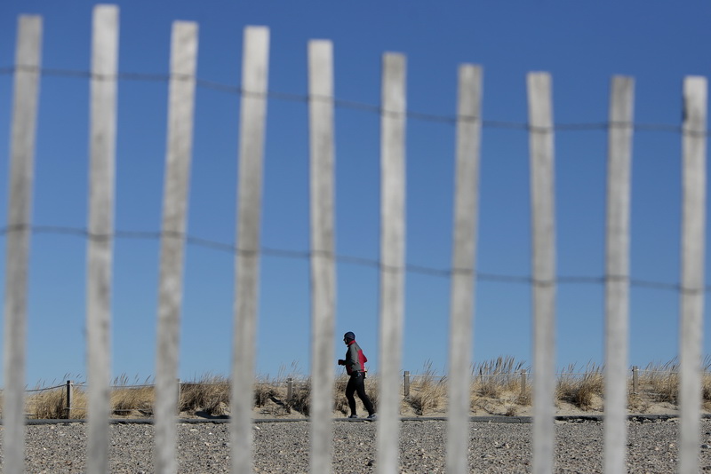 A man goes for a morning run at Horseneck Beach in Westport, MA as seen through the beach erosion fencing on the sand. PHOTO PETER PEREIRA