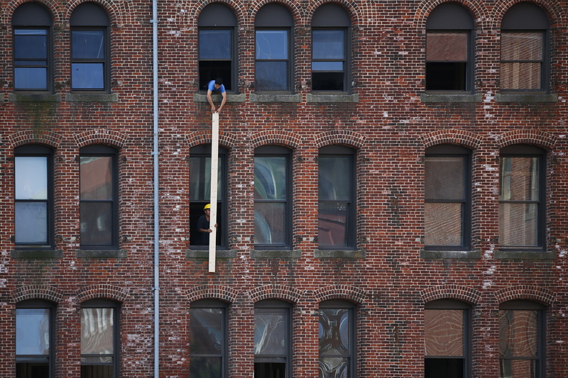 Workmen transfer a plank from the second floor to the third floor of a building under renovation in downtown New Bedford, MA.  PHOTO PETER PEREIRA