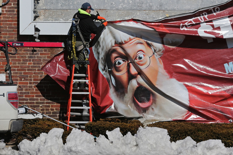 Santa is not too pleased as a Clear Channel technician removes a Holiday season billboard from the side of a building on S Second Street in New Bedford, MA. PHOTO PETER PEREIRA