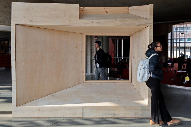 A student, right, waits for her coffee order to be ready, while another walks past the aperture in the 'Breuer Window' mock-up currently installed in the UMass Dartmouth library.  The Breuer Window presents a three-quarter scale model of a Lincoln Campus Center window facade panel, allowing visitors to get closer to a detail used in Brutalist architecture buildings, of which UMass Dartmouth is one designed by Paul Rudolph in 1963. PHOTO PETER PEREIRA